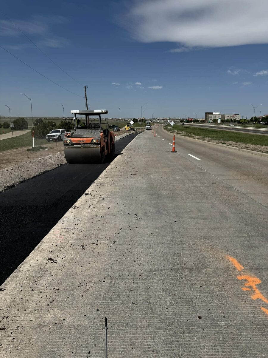 Roller compacting fresh asphalt on a road paving project
