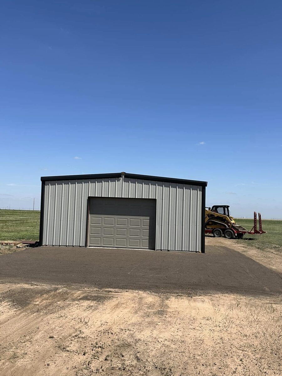 New asphalt driveway pad in front of a metal building