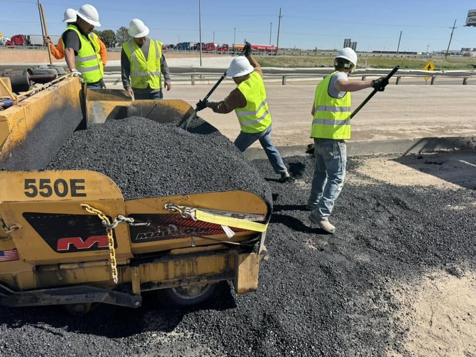 Crew of workers shoveling hot asphalt during a roadway repair